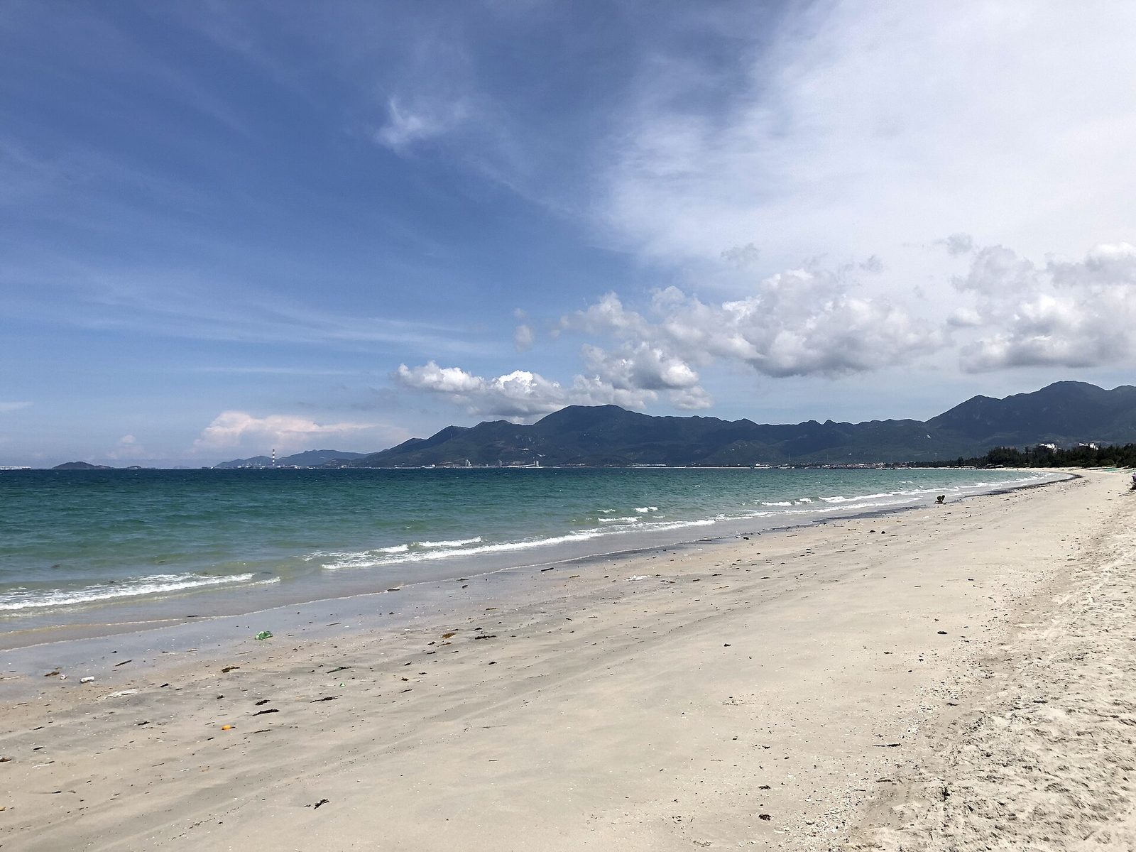 Bãi biển Dốc Lết, Ninh Hoà — phía Nam vịnh Vân Phong vừa có bãi biển du lịch vừa nằm sát khu công nghiệp; đất ở đây đi theo cầu nào tuỳ nó cách cái nào gần hơn. (Ảnh: Victor311, CC BY-SA 4.0)